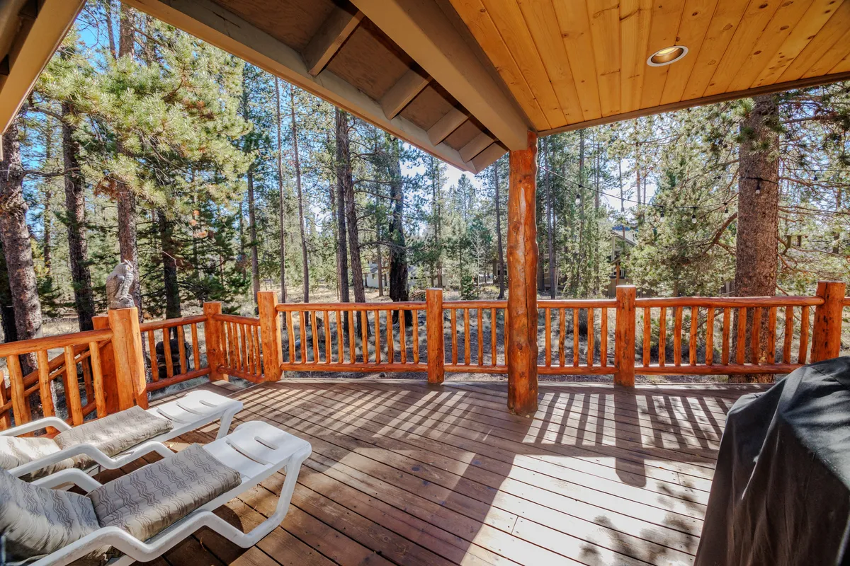 A tranquil outdoor scene with lounge chairs on a wooden deck, overlooking a lush forest. The setup invites guests to unwind, enjoy quiet moments after a day of exploration, or share stories under the open sky.