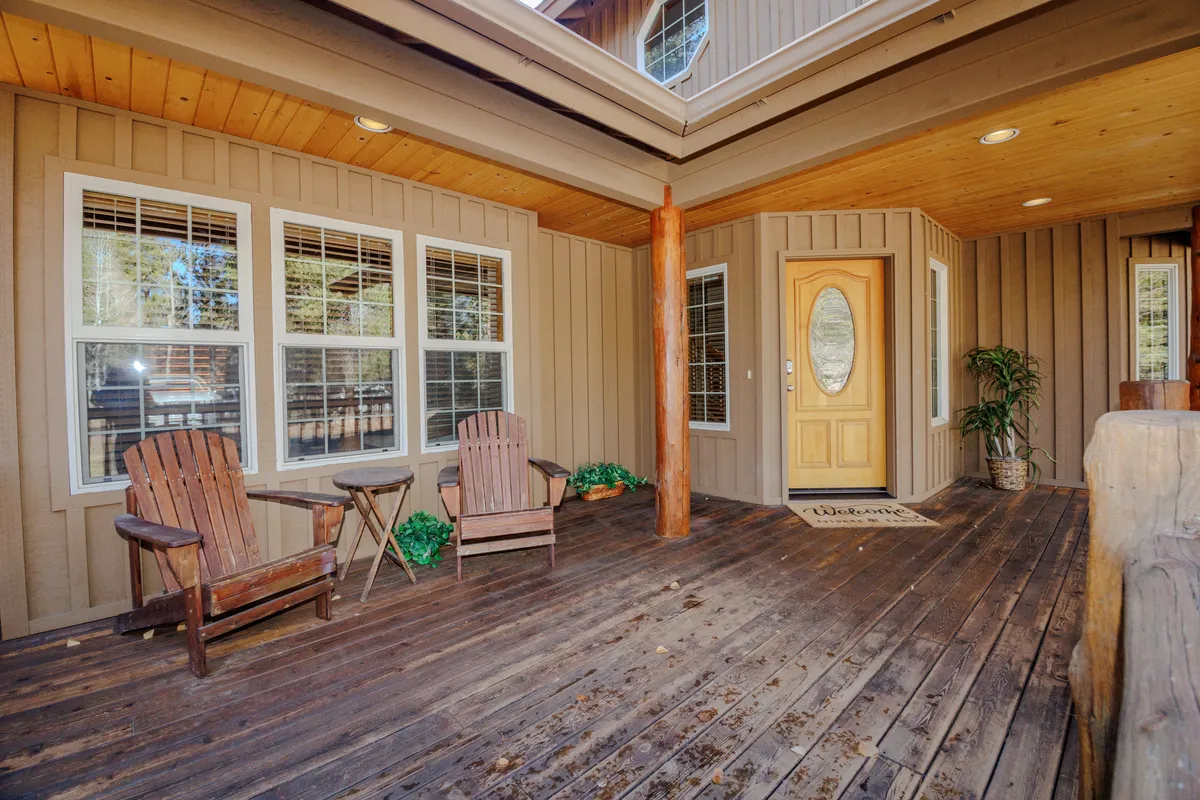 This image highlights the home's interior entry area with a view out to nature, wooden pillars, and a welcoming seating space. Large windows let in natural light and visually link the home’s interior to the outdoors.