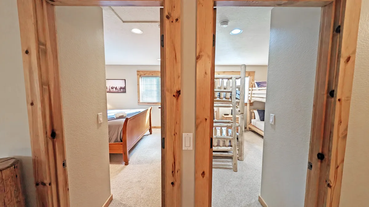 A family-friendly bedroom with a wooden-framed main bed and a set of sturdy, natural wood bunk beds, perfect for children or groups. The inviting setting encourages bedtime stories and shared laughter, capturing the playful and communal spirit of the bunk room mentioned in the section.